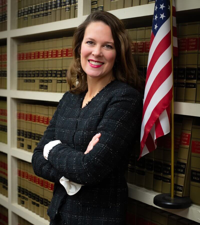 Attorney Jill Penn standing in front of law books and US flag