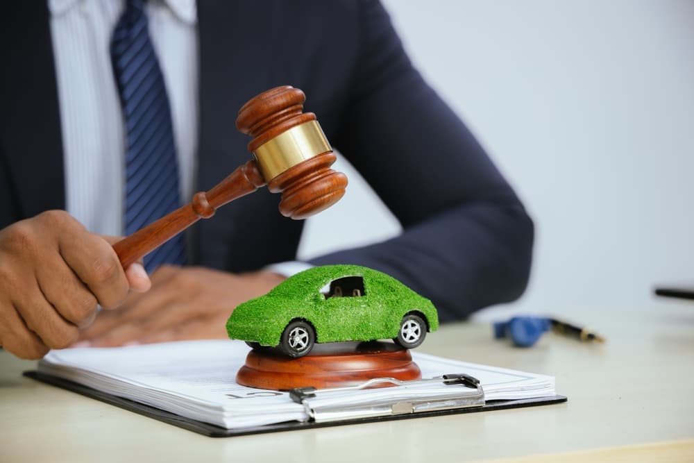 In a courtroom, a judge with a gavel presides over a car accident case. Lawyers present evidence and legal documents.