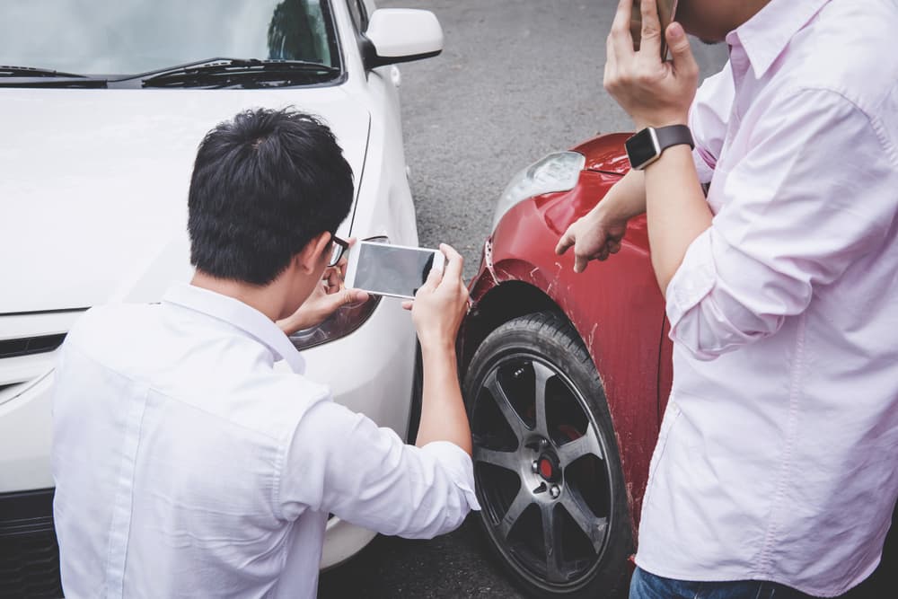 Two drivers man arguing after a car traffic accident collision and making phone call to Insurance Agent and take a photo.