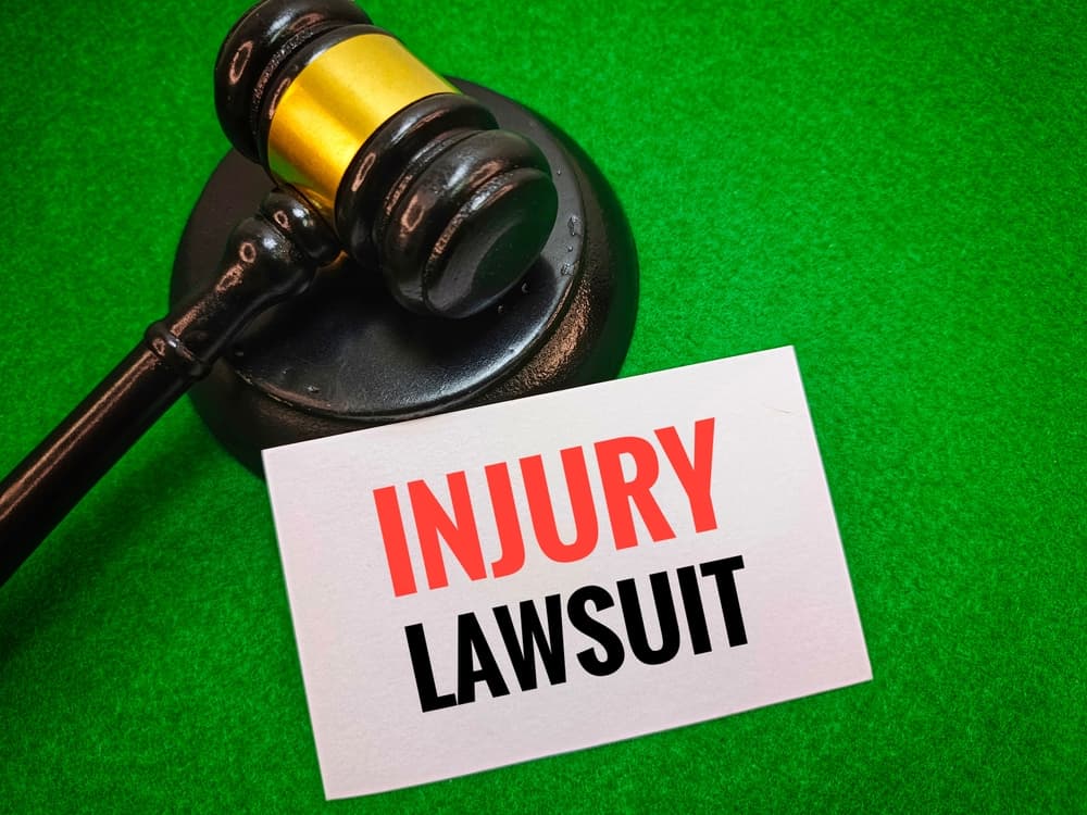 Text Injury Lawsuit on a white paper with White Paper Card and Wooden Judge Gavel