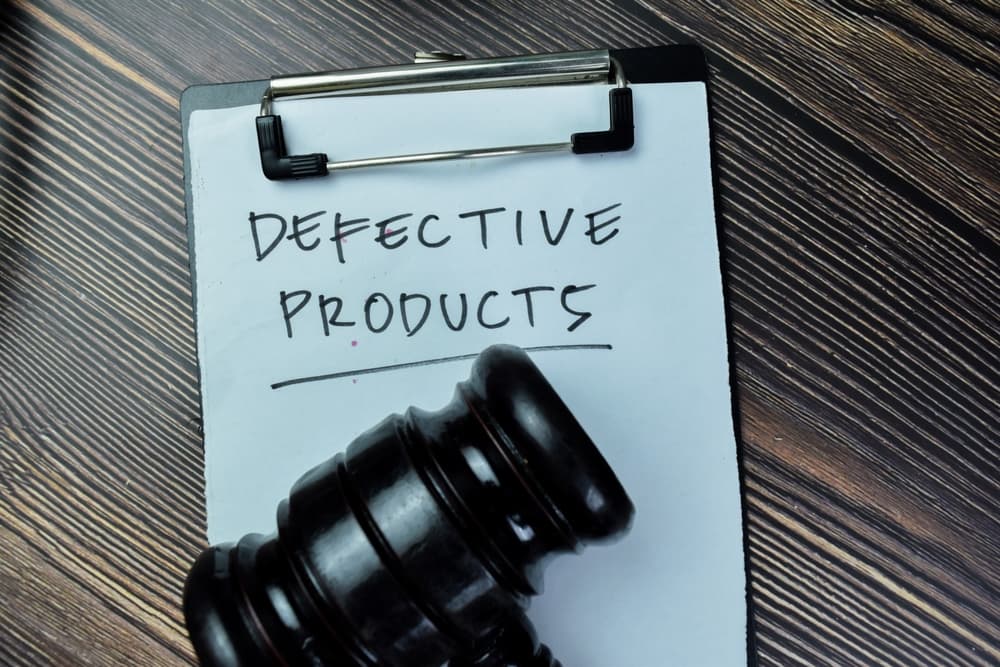Defective Products write on paperwork with gavel isolated on Wooden Table.